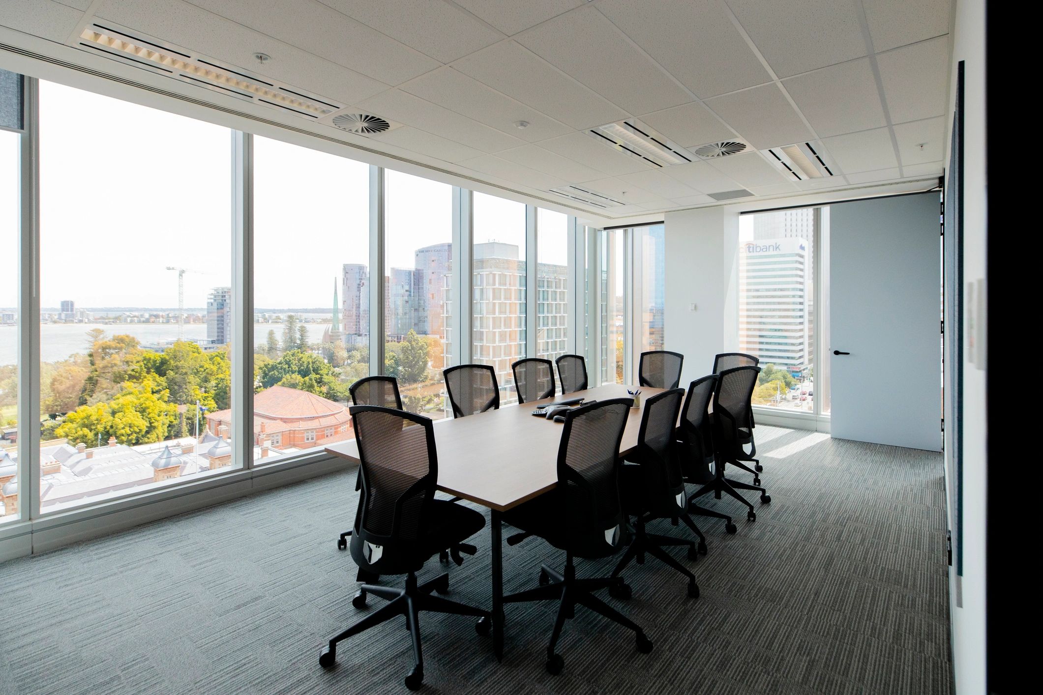 Boardroom table set for a meeting with a city view through large windows